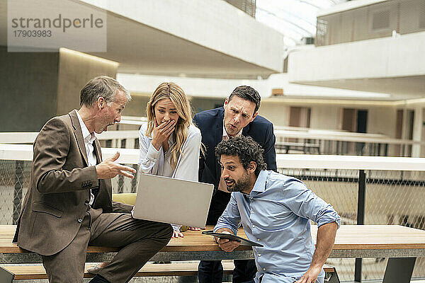 Überraschte Geschäftskollegen diskutieren am Laptop im Flur