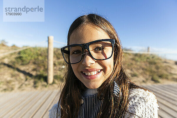 Glückliches Mädchen mit Brille am Strand an einem sonnigen Tag
