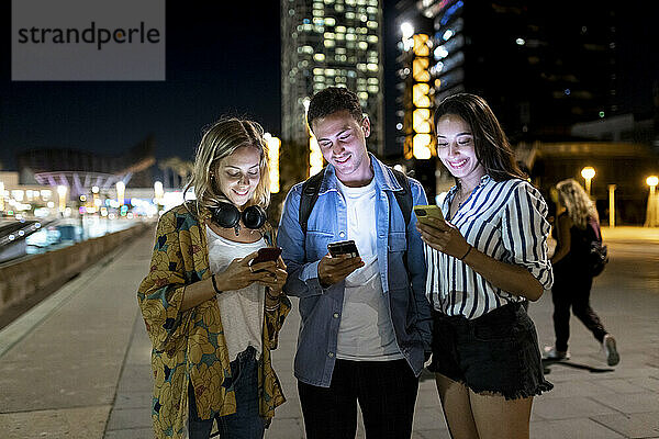 Lächelnde Männer und Frauen surfen per Smartphone im Internet in der Stadt