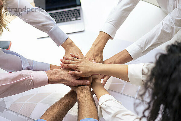 Business colleagues stacking hands in meeting at office