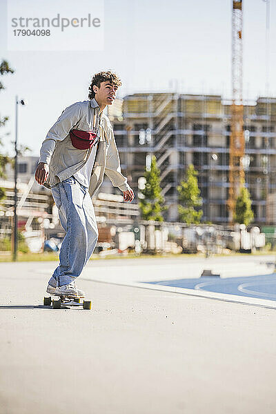 Junger Mann fährt Skateboard auf Fußweg