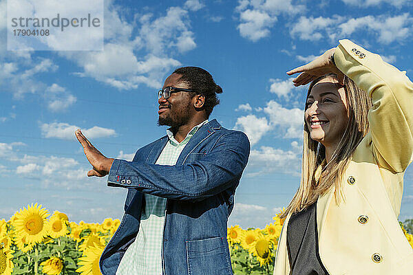 Happy businessman with businesswoman in field on sunny day