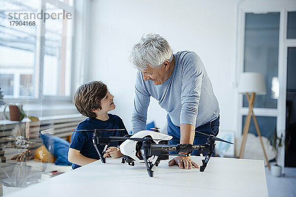 Großvater und Enkel unterhalten sich mit Drohne auf dem Tisch im Wohnzimmer