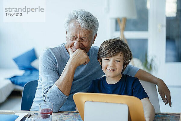 Glücklicher älterer Mann mit der Hand am Kinn von seinem süßen Enkel zu Hause
