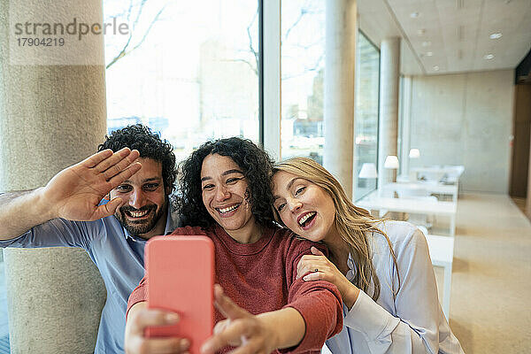Cheerful colleagues taking selfie on mobile phone