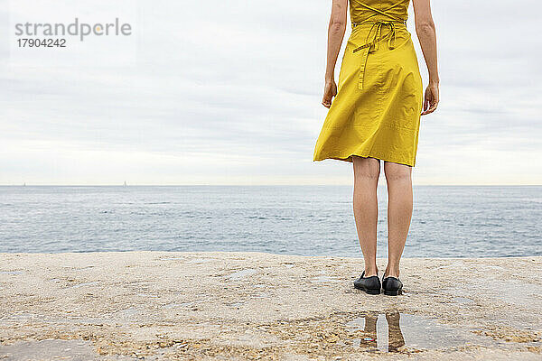 Frau steht auf der Promenade am Meer