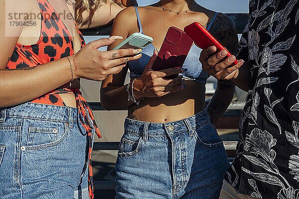 Männer und Frauen nutzen an sonnigen Tagen Smartphones