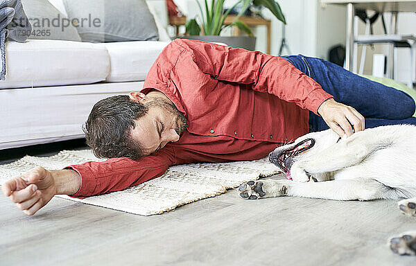 Mann entspannt sich mit Hund zu Hause auf dem Boden
