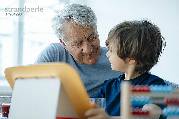 Lächelnder Großvater spricht mit Enkel zu Hause