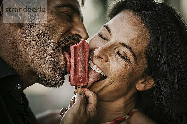 Carefree couple with eyes closed licking ice cream