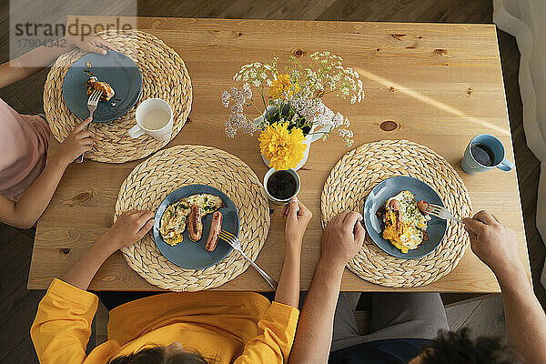Father with daughters eating breakfast on table