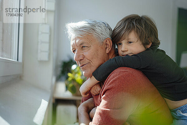 Nachdenklicher älterer Mann mit Enkel zu Hause