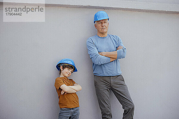 Enkel und Großvater mit verschränkten Armen vor der Wand