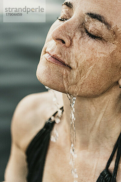 Reife Frau mit Wasser im Gesicht