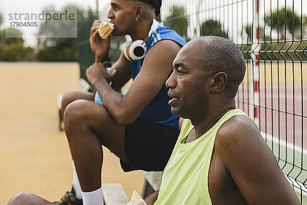 Reifer Mann macht Pause und entspannt sich mit seinem Sohn auf dem Basketballplatz