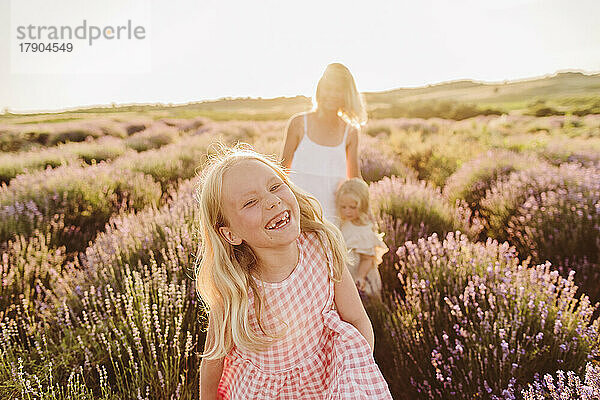 Glückliches Mädchen  das mit Mutter und Schwester im Lavendelfeld genießt