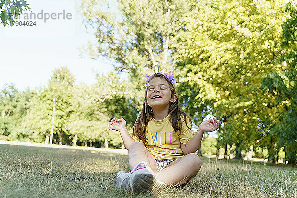 Cheerful girl sitting on grass at park