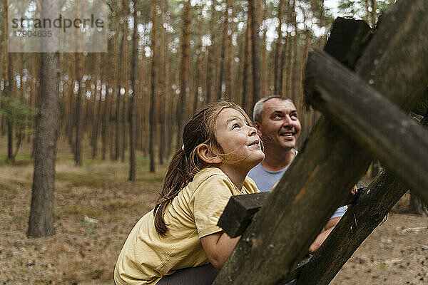 Lächelndes Mädchen klettert Leiter im Wald