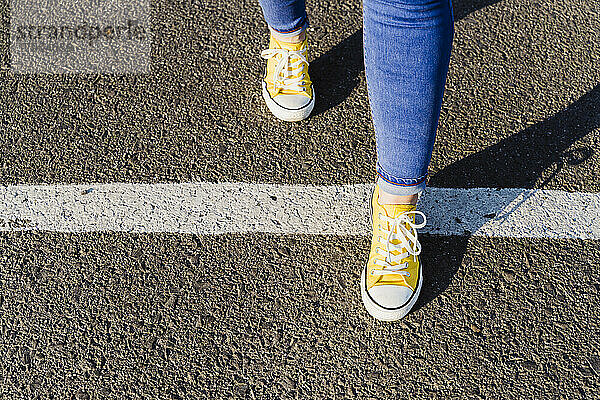 Frau steigt über weiße Linie auf Asphalt