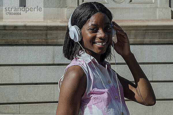 Glückliche Frau  die an einem sonnigen Tag Musik über Kopfhörer hört
