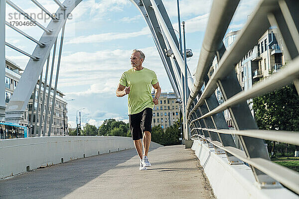 Reifer Mann joggt auf Brücke in der Stadt