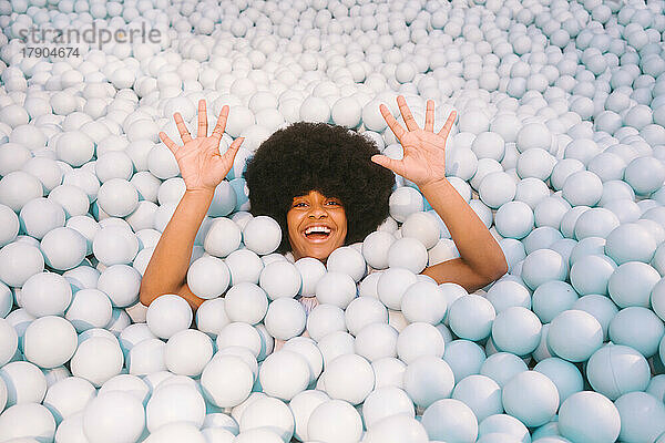 Smiling young woman waving in ball pool