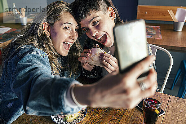 Glückliche Frau mit Freundin macht Selfie per Smartphone