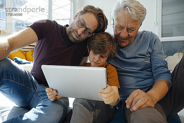 Mehrgenerationenfamilie schaut sich zu Hause einen Film auf einem Tablet-PC an