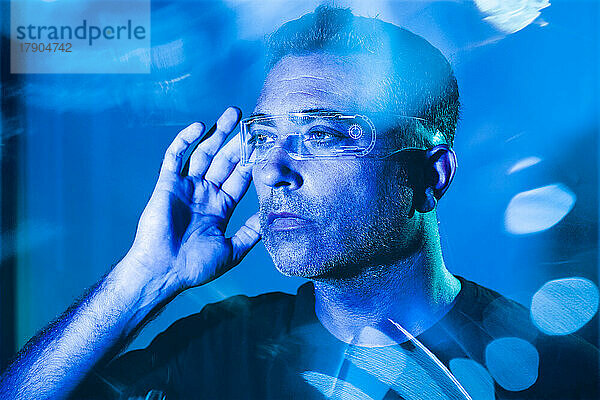 Mann passt eine futuristische Brille an  die mit blauem Licht beleuchtet ist