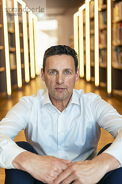 Mann sitzt in beleuchteter Bibliothek an der Universität