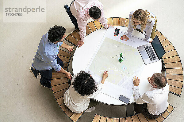 Business people discussing with each other over diagram on table in office