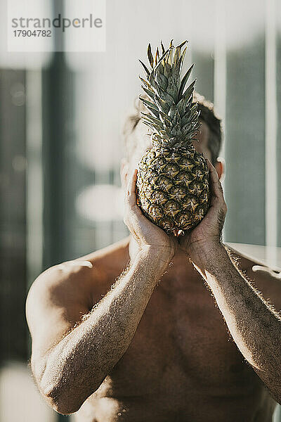 Mann bedeckt Gesicht mit Ananas