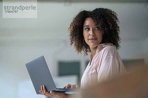 Nachdenkliche Geschäftsfrau mit Laptop im Büro