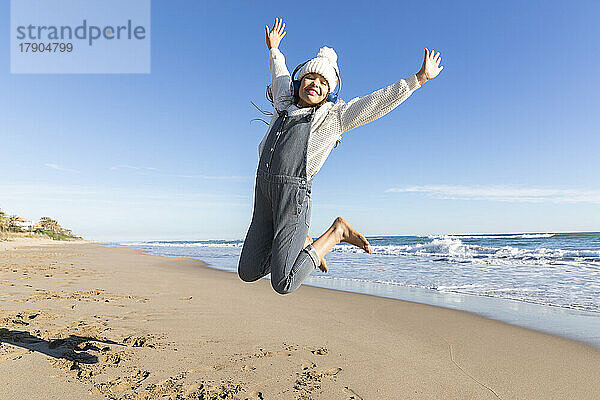 Fröhliches Mädchen springt am Strand in die Luft