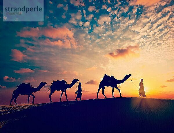 Vintage Retro-Effekt gefiltert Hipster-Stil Bild von Rajasthan Reise Hintergrund  zwei indische Kamele Kameltreiber mit Kamelen Silhouetten in den Dünen der Wüste Thar bei Sonnenuntergang. Jaisalmer  Rajasthan  Indien  Asien