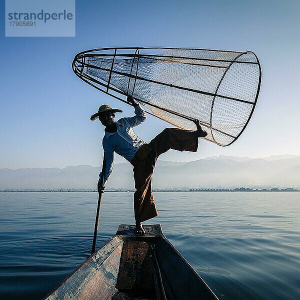 Myanmar Reiseattraktion Wahrzeichen  traditionelle birmanische Fischer Silhouette Balancieren mit Fischernetz am Inle-See in Myanmar berühmt für ihre unverwechselbaren einbeinigen Ruderstil  Blick vom Boot