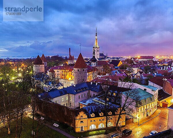 Luftaufnahme der mittelalterlichen Altstadt von Tallinn mit der St. -Olaf-Kirche und der abendlich beleuchteten Stadtmauer von Tallinn mit dramatischer Wolkenlandschaft  Estland  Europa