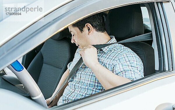 Nahaufnahme des Fahrers beim Anlegen des Sicherheitsgurtes. Konzept eines Fahrers in seinem Auto beim Anlegen des Sicherheitsgurtes. Seitenansicht einer Person beim Anlegen des Sicherheitsgurtes  Glücklicher Fahrer beim Anlegen des Sicherheitsgurtes