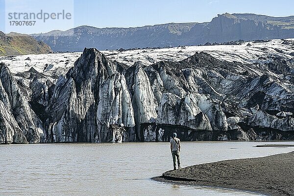 Tourist am Seeufer einer Gletscherlagune  Gletscherzunge mit Gletscherspalten und See  Sólheimajökull  Südisland  Island  Europa