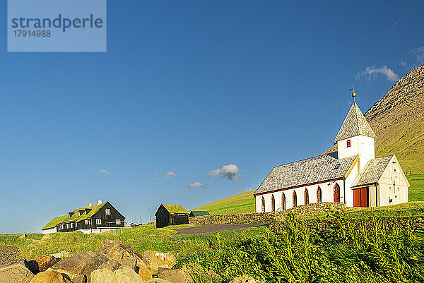Blick auf die Kirche und Grasdachhäuser inmitten grüner Wiesen von Vidareidi  Insel Vidoy  Färöer  Dänemark  Europa