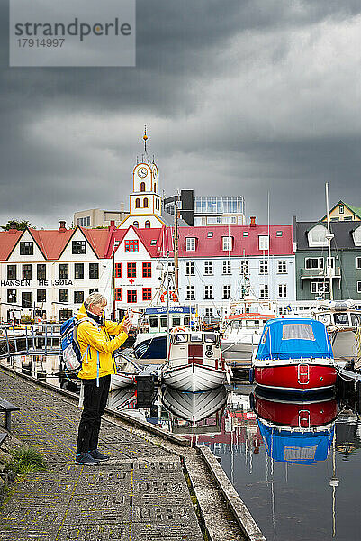 Ein Tourist macht ein Foto mit einem Smartphone vom Pier des Hafens von Torshavn  Insel Streymoy  Färöer Inseln  Dänemark  Europa