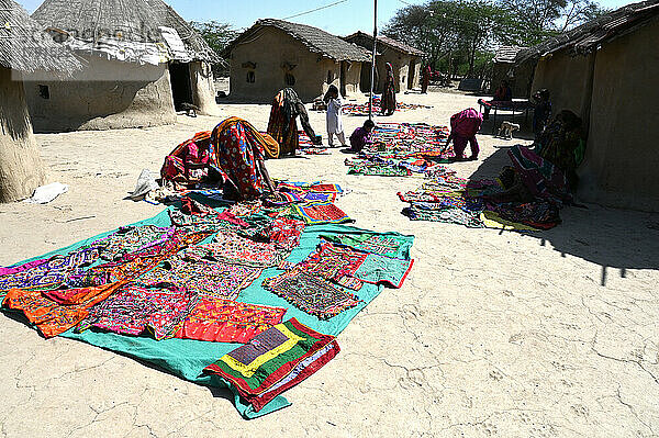 Stammesfrauen legen ihre Stammesstickereien vor den Häusern mit Lehmwänden in ihrem Stammesdorf aus  Kachchh  Gujarat  Indien  Asien