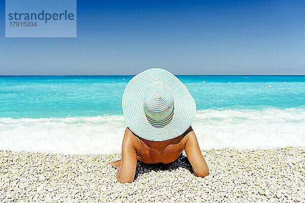 Unbekümmerte Frau mit Strohhut beim Sonnenbaden an einem idyllischen Strand  Kefalonia  Ionische Inseln  Griechische Inseln  Griechenland  Europa