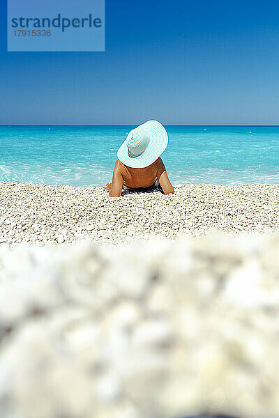 Frau mit Strohhut betrachtet das Meer am Strand im Sommer  Kefalonia  Ionische Inseln  Griechische Inseln  Griechenland  Europa