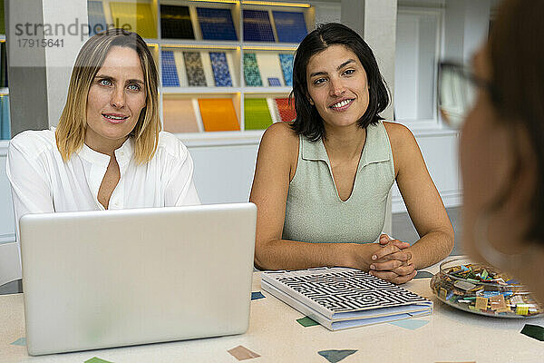 Mid-shot von zwei verschiedenen weiblichen Geschäftsinhabern  die am Schreibtisch sitzen  während sie einen Kunden befragen