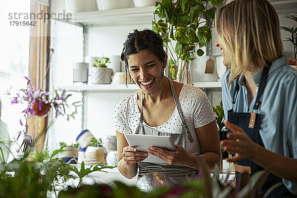 Fröhliche Blumenladenbesitzerin mit digitalem Tablet