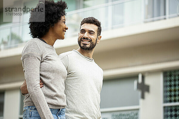 Glückliches junges erwachsenes Paar geht auf dem Bürgersteig