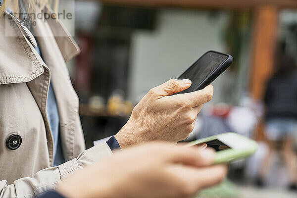 Nahaufnahme von Händen  die Smartphones bei der Arbeit im Freien halten