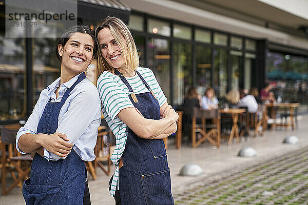 Porträt von zwei glücklichen Restaurantbesitzerinnen  die vor ihrem Restaurant posieren und Spaß haben