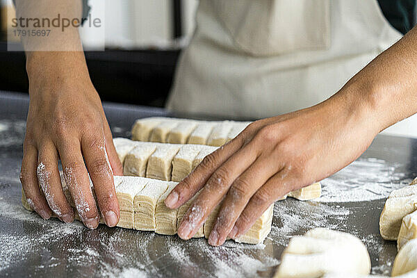 Nahaufnahme der Hände einer Bäckerin bei der Herstellung von Gebäck